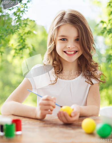 Image of happy smiling girl coloring easter eggs