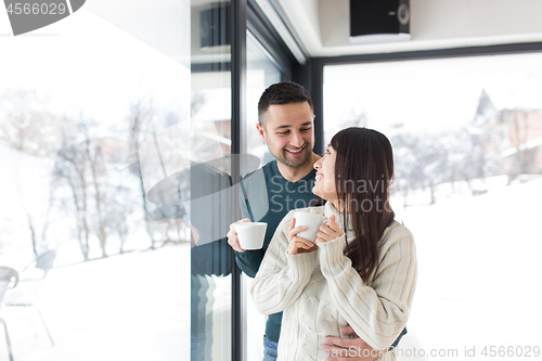 Image of multiethnic couple enjoying morning coffee by the window