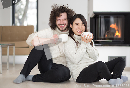 Image of happy multiethnic couple  in front of fireplace