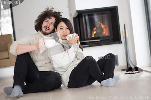 Image of happy multiethnic couple  in front of fireplace