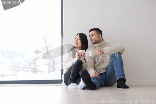 Image of multiethnic couple enjoying morning coffee by the window