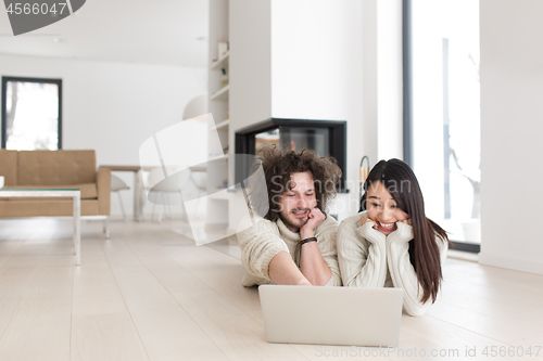 Image of young multiethnic couple using a laptop on the floor