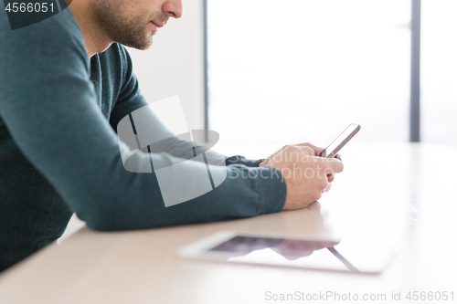 Image of Young casual businessman using smartphone