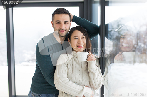 Image of multiethnic couple enjoying morning coffee by the window