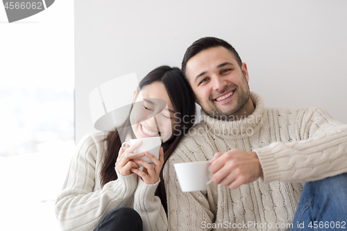 Image of multiethnic couple enjoying morning coffee by the window