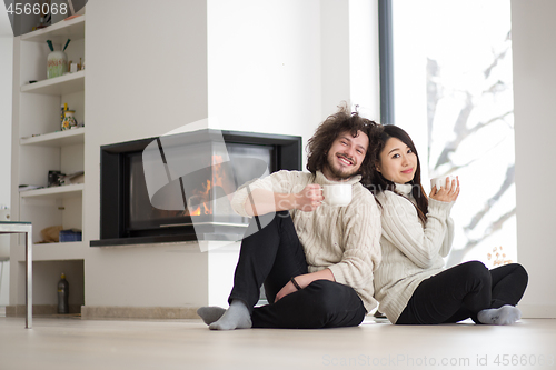 Image of happy multiethnic couple  in front of fireplace