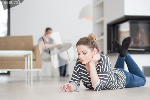 Image of woman using tablet computer in front of fireplace