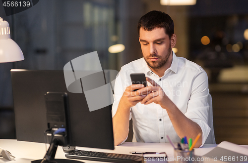 Image of businessman with smartphone and computer at office