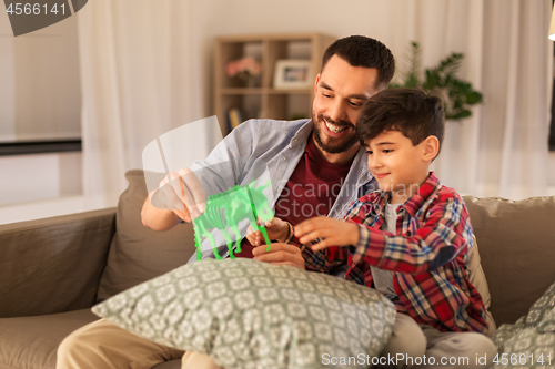 Image of father and son playing with toy dinosaur at home