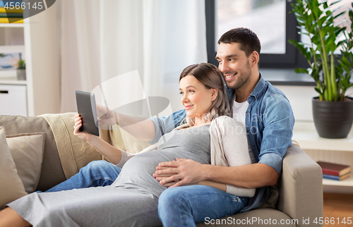 Image of man and pregnant woman with tablet pc at home