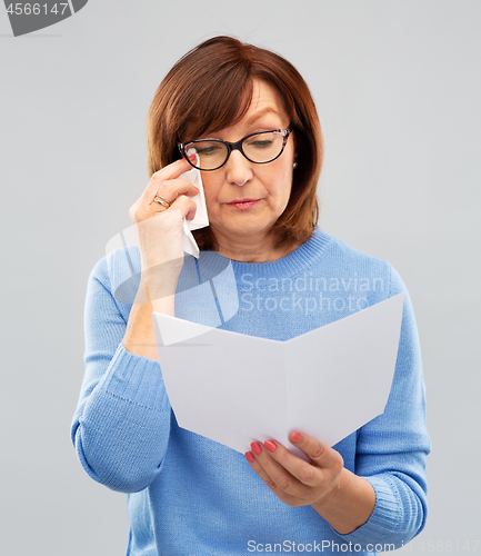 Image of sad senior woman reading letter and crying