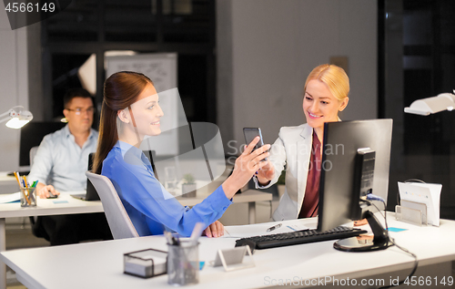 Image of businesswomen with smartphone late at night office