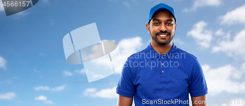 Image of happy indian delivery man in blue uniform over sky