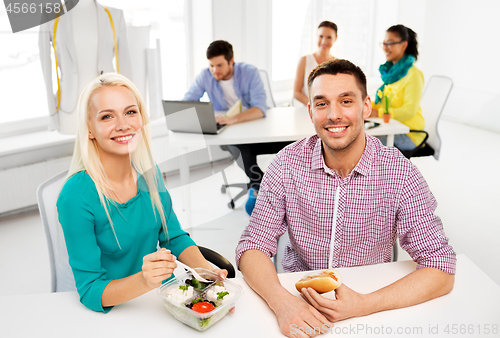 Image of happy colleagues having lunch and eating at office