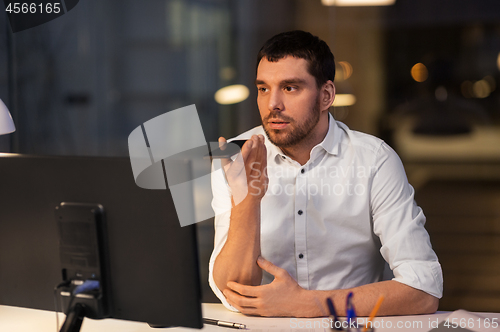 Image of businessman recording voice message on smartphone