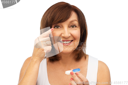 Image of happy senior woman applying contact lenses