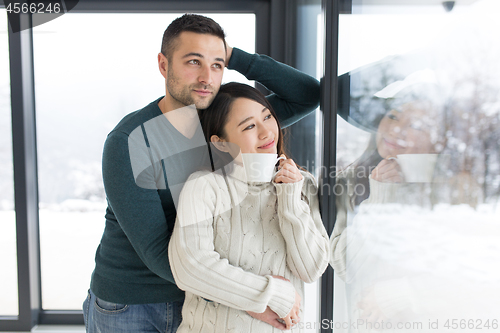 Image of multiethnic couple enjoying morning coffee by the window