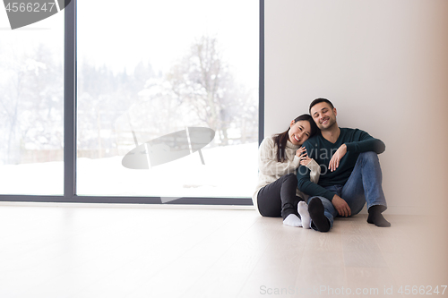 Image of multiethnic couple sitting on the floor near window at home