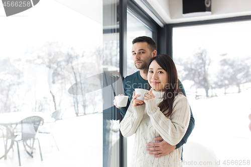 Image of multiethnic couple enjoying morning coffee by the window