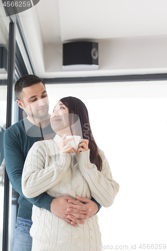 Image of multiethnic couple enjoying morning coffee by the window