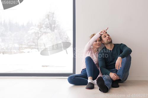 Image of young couple sitting on the floor near window at home