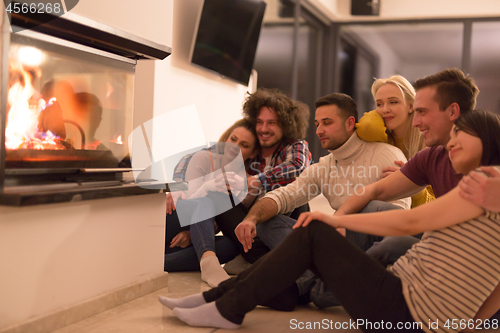 Image of multiethnic couples sitting in front of fireplace