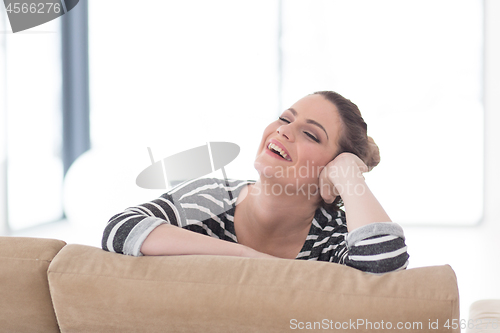 Image of portrait of a young beautiful woman sitting on the sofa