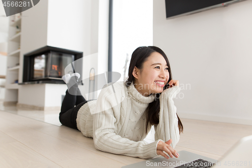 Image of young Asian woman using laptop on the floor