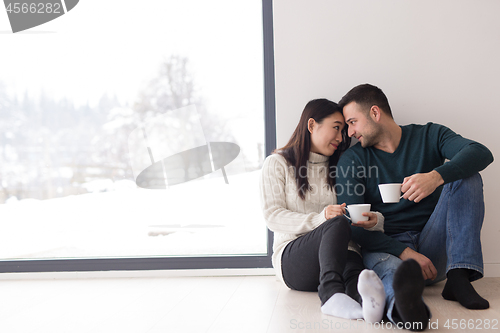 Image of multiethnic couple enjoying morning coffee by the window