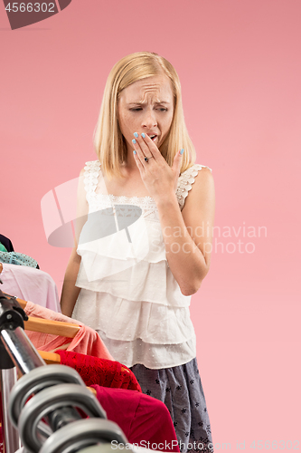 Image of The young unhappy pretty girl looking at dresses and try on it while choosing at shop