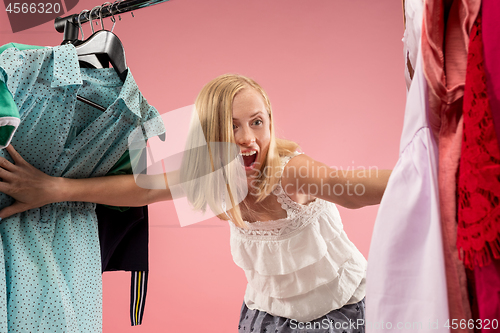 Image of The young pretty girl looking at dresses and try on it while choosing at shop