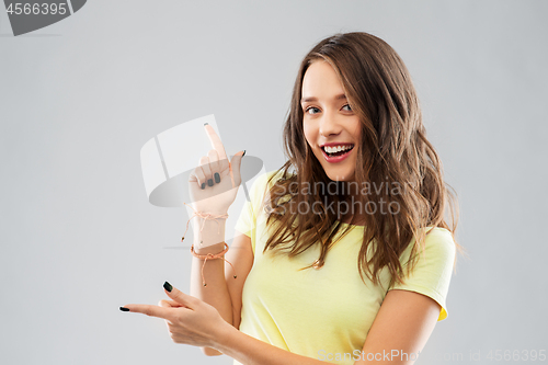 Image of happy teenage girl pointing to something imaginary