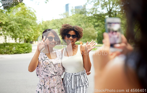 Image of woman photographing her friends in summer park