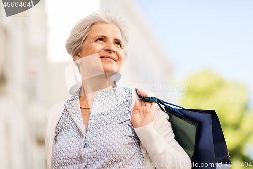 Image of senior woman with shopping bags in city