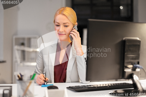 Image of businesswoman calling on sartphone at night office