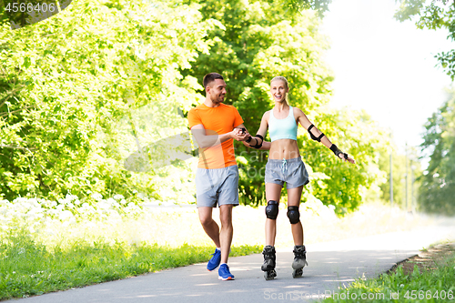 Image of couple with roller skates riding in summer park