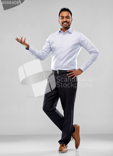 Image of indian businessman holding something over grey