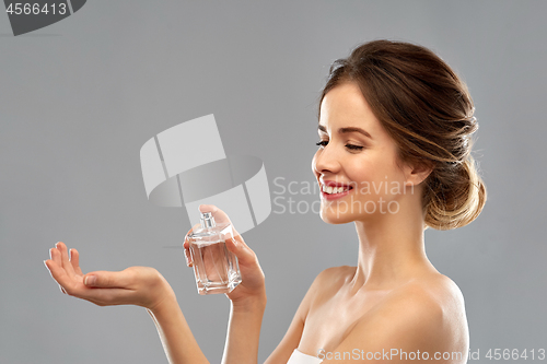 Image of happy woman with perfume over gray background