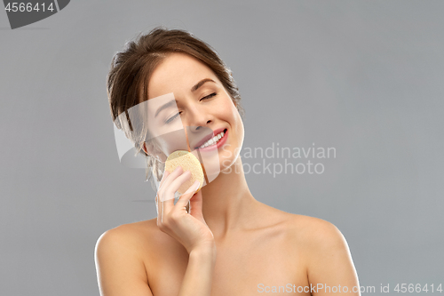 Image of young woman cleaning face with exfoliating sponge