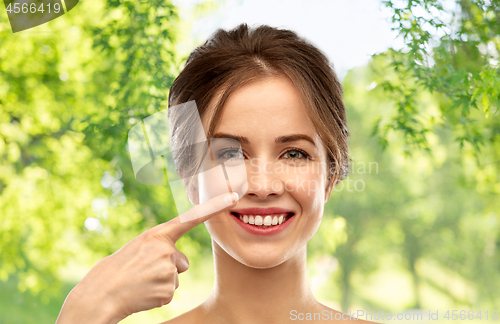 Image of beautiful young woman pointing to her nose