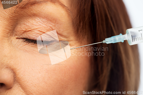 Image of close up of senior woman face and syringe