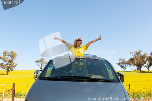 Image of Happy woman standing out the sunroof of her 4wd car by canola fi