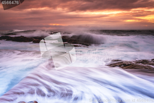 Image of Large waves wash into the tidal ocean pool at sunrise