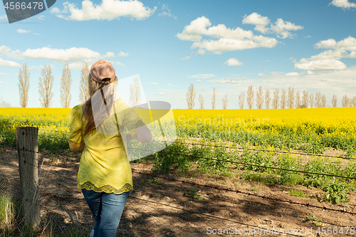 Image of Female admiring the rural fields of canola in flower during spri