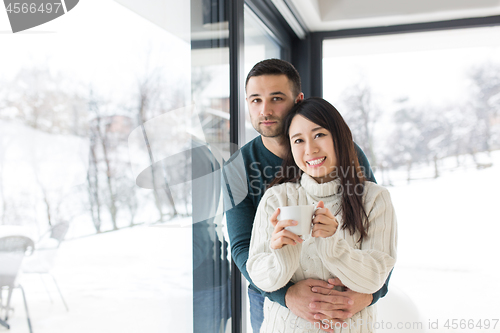 Image of multiethnic couple enjoying morning coffee by the window