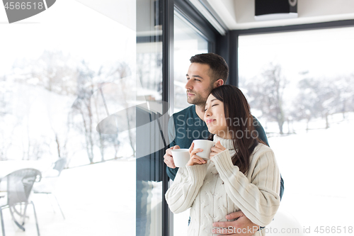 Image of multiethnic couple enjoying morning coffee by the window