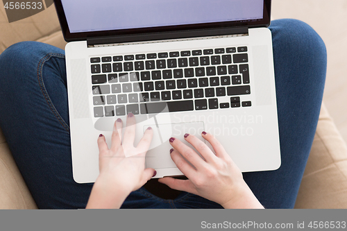 Image of young woman on sofa at home websurfing