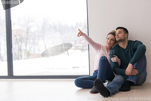 Image of young couple sitting on the floor near window at home