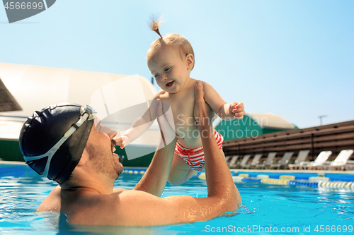 Image of Happy family having fun by the swimming pool