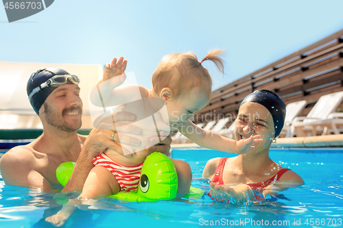 Image of Happy family having fun by the swimming pool